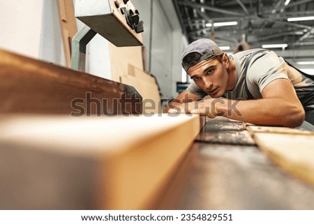 Young carpenter working on woodworking machines in the furniture factory Royalty-Free Stock Photo #2354829551