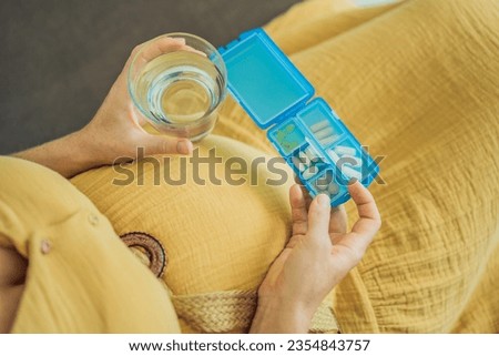 Prenatal Vitamins. Portrait Of Beautiful Smiling Pregnant Woman Holding Pill Box and a glass of water, Taking Supplements For Healthy Pregnancy While Sitting On Couch At Home, Free Space Royalty-Free Stock Photo #2354843757