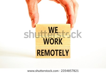 We work remotely symbol. Concept words We work remotely on wooden block. Beautiful white table white background. Businessman hand. Business we work remotely concept. Copy space.