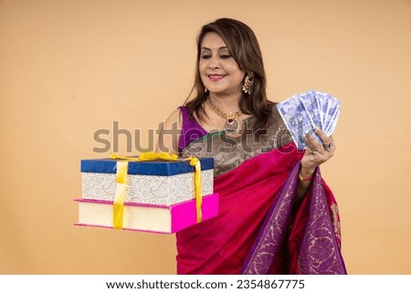 Indian beautiful women with Indian rupees and gift boxes, standing isolated over white background. wearing traditional colorful saree in diwali festival. celebrating of festive season theme.