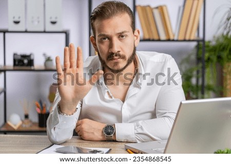 Stop. Lebanese businessman working on laptop, warning of finish, prohibited access, declining communication, body language, rejection, danger trouble. Manager man freelancer at home office workplace Royalty-Free Stock Photo #2354868545