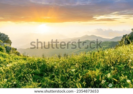 sceniv view from a top of a rocky mountain to amazing highland landscape with valley, peaks of mountains and beautiful cloudy sunset or sunrise