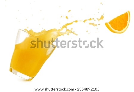 Tilted drinking glass with orange juice spilling out and a flying orange slice isolated on white background. Real studio photo. Royalty-Free Stock Photo #2354892105