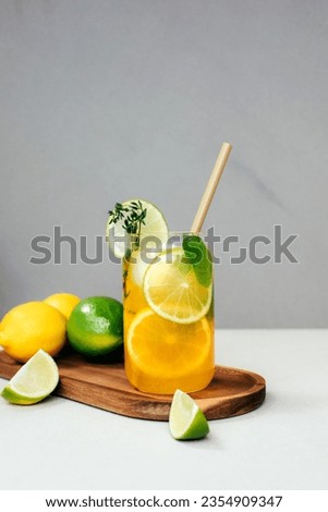 Drink with orange lemon and lime in glass transparent glasses on a concrete background. Lemonade with ice. Front view