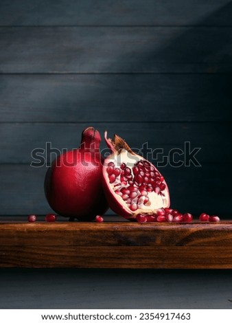 Image of Still Life with Pomegranate. Dark wood background, antique wooden table. Royalty-Free Stock Photo #2354917463