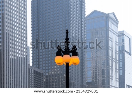Tall lamp post with lit ball lights against tall modern buildings in downtown Chicago