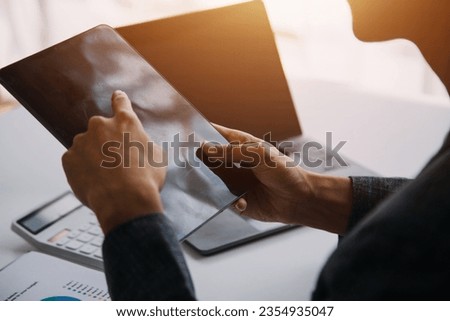 Entrepreneur Asian businessman and businesswoman discussing new business project in tablet in modern Meeting In Modern Office, Asian business casual concept.