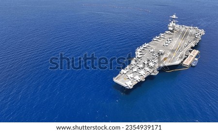 Aerial drone photo of USS Gerald R. Ford latest technology nuclear powered aircraft carrier anchored in deep blue open ocean sea Royalty-Free Stock Photo #2354939171
