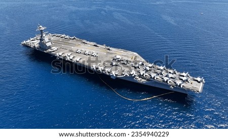 Aerial drone photo of USS Gerald R. Ford latest technology nuclear powered aircraft carrier anchored in deep blue open ocean sea Royalty-Free Stock Photo #2354940229