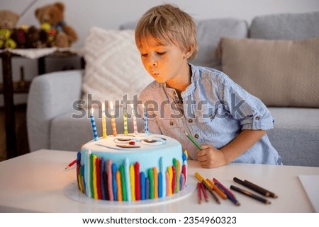 Cute preschool child, blowing candles on his cake, six years old, going to school. Kid ready for first day at school