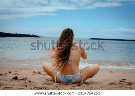 A beautiful tall long-legged girl in a swimsuit meditates on the sandy shore of the Georgian sea