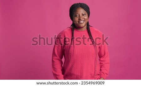 Stylish african american woman posing in a vibrant pink sweater for a stunning photo. Portrait of a young black woman in a trendy outfit smiling at camera for a picture.