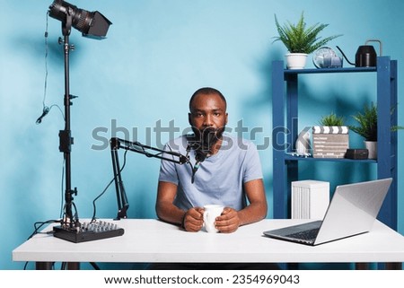 Blogger live streaming and broadcasting online for vlog video channel while looking at camera. African american man vlogger creating digital content and speaking on camera