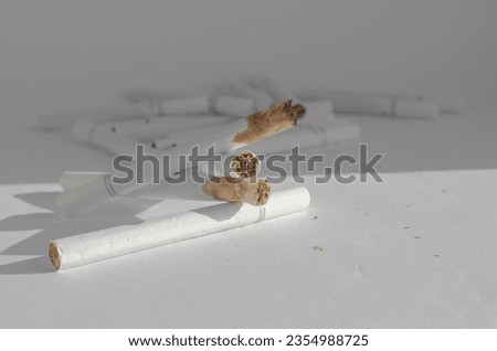 Detail of cigarettes on a white surface, symbolizing the health risks and illnesses associated with smoking. Royalty-Free Stock Photo #2354988725