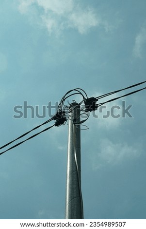 an iron pole connecting the wires, against a blue sky in the background