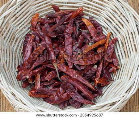 a photography of a basket of dried chilis on a table, shopping basket of dried chilis on a wooden table.