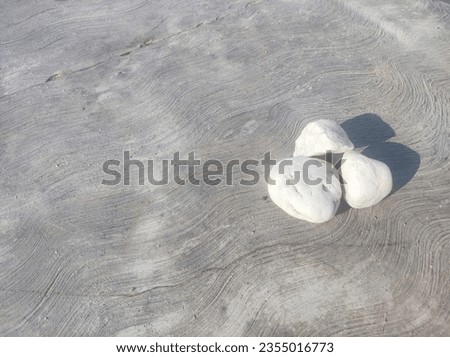 three small white stone arrange on textured concrete