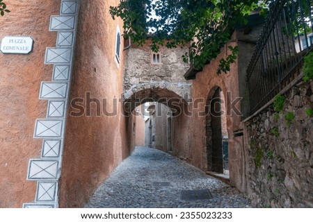 Lane leading from Piazza Comunale betweem exterior walls and under stone arch connecting bridge in Como.