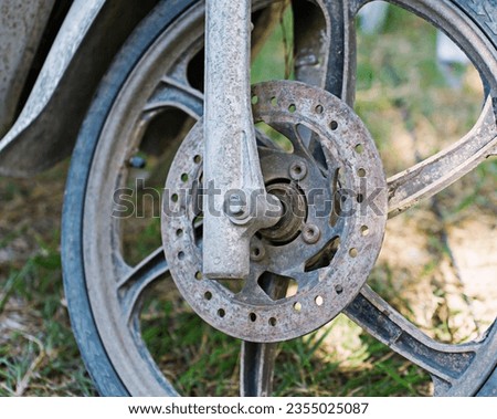 The front disc brake system of a motorbike is old and rusted and is not safe to use.