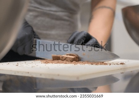 chef cutting chocolate fudge candy for cheesecake preparation close up shots, caterer professional kitchen
