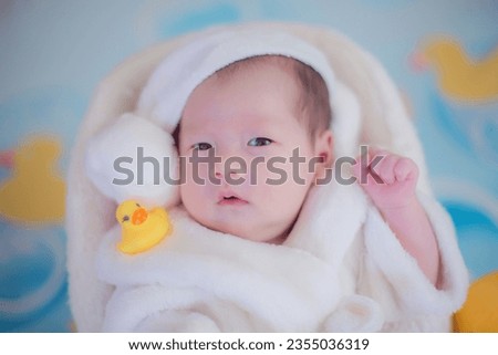 The adorable Asian newborn baby girl is looking at the camera with a curious expression.