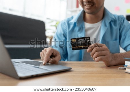 Young asian businessman holding credit card and using mobile phone, laptop for digital banking, internet payment, online shopping via mobile app, financial technology, ecommerce concept
