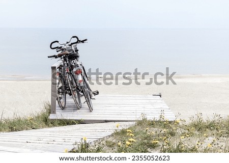 Three bicycles parked on wooden rest place by empty beach. Desaturated horizontally oriented picture