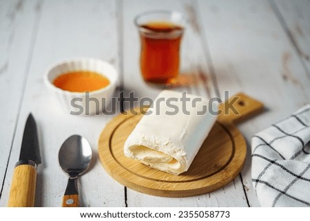 Close up picture of white cream milky kaymak butter roll poured tea on wooden plate.