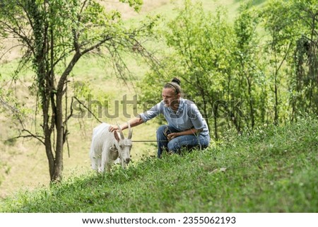 woman takes the goat out to graze