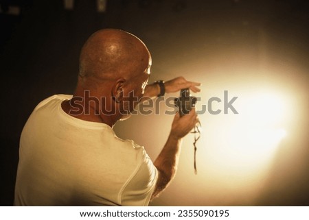 A cameraman measures the light with an exposure meter for film work.
