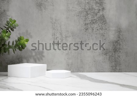 Cosmetic background with podium. Textured gray background and white marble support. Plants on the sides.