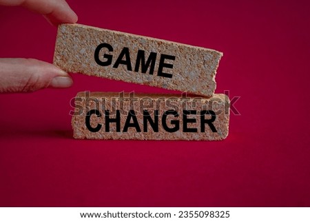 Brick blocks with words Game changer. Beautiful red background, copy space. Game changer business or political change concept and disruptive innovation.