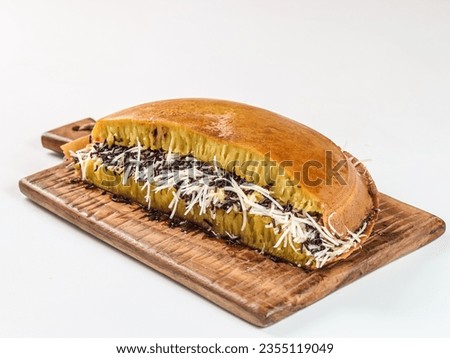 Martabak manis or terang bulan is indonesian sweet pancake, with yellow color and filled with chocolate chips, cheese, fruit jam, butter and peanut on white background. Royalty-Free Stock Photo #2355119049