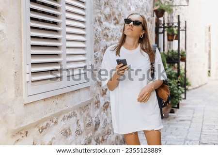 A young woman walks along the old streets and looks at tourist places on her phone. Navigation using a smartphone