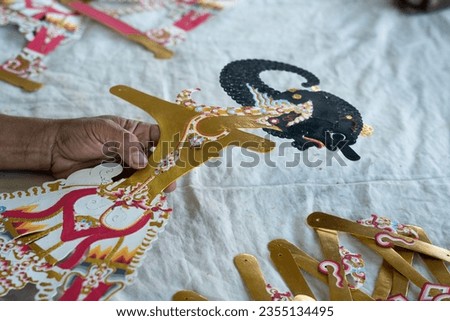 Process of making Indonesian Wayang puppets used in traditional theatre. Warm colors, black and gold, artist hands. Picture was taken in a natural light.