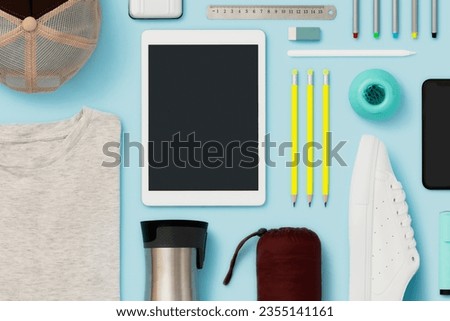 Back to school flat lay on blue background with blank screen digital tablet. Personal accessories and school supplies flat lay