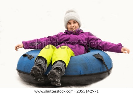 Active girl sliding down the hill on snow tube. Cute little happy child having fun outdoors in winter on sledge . Healthy excited kid tubing snowy downhill, family winter time