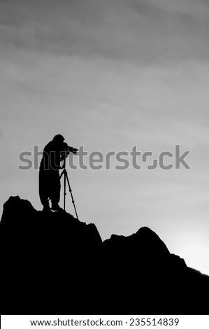 Black and white image style silhouette image of the photographer on the mountain rock.