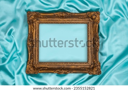 Beautiful classic decorated golden frame on blue, turquoise silky satin. Luxury turquoise background with blurred copy space for design. Web element sign