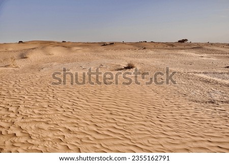 A scenic view of desert against sky under the clear blue sky with the sun shining bright