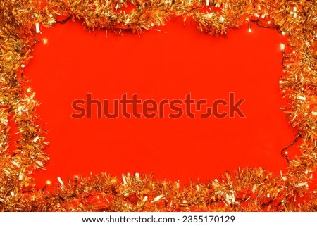 Christmas frame made of tinsel and Christmas electric lights on red background