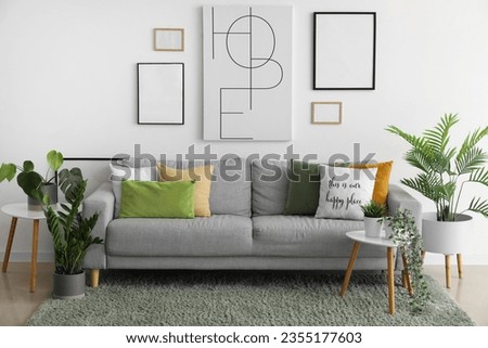 Interior of living room with cozy sofa, paintings and houseplants Royalty-Free Stock Photo #2355177603