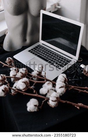 laptop beautiful photo on a black tablecloth with cotton flowers and flat lay perfume