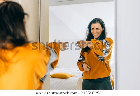 
Self confident single woman pointing finger at reflection in mirror dancing and felling good. Independent person with high self esteem talk positive I can do it motivation. Royalty-Free Stock Photo #2355182561