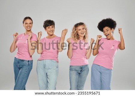 breast cancer awareness, excited interracial women with pink ribbons on grey, diversity, cancer free Royalty-Free Stock Photo #2355195671