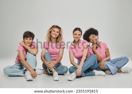 happy interracial women different age sitting on grey backdrop, breast cancer awareness, cancer free Royalty-Free Stock Photo #2355195815