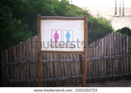 An illustration of a beach scene featuring a rustic wooden sign that reads "Public Toilet" in large block lettering