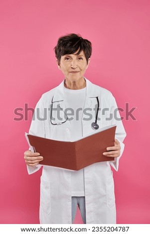 mature oncologist, female doctor holding folder, breast cancer awareness concept, diagnosis Royalty-Free Stock Photo #2355204787