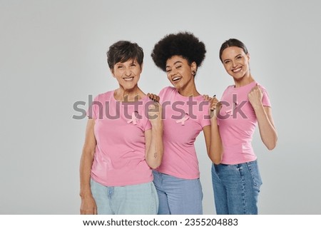 breast cancer awareness, joyful multicultural women smiling on grey backdrop, different generations Royalty-Free Stock Photo #2355204883