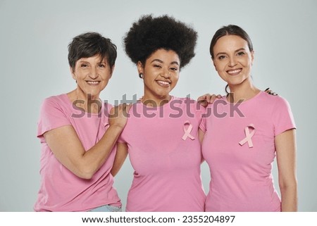 breast cancer awareness, interracial women smiling on grey backdrop, different generations, portrait Royalty-Free Stock Photo #2355204897